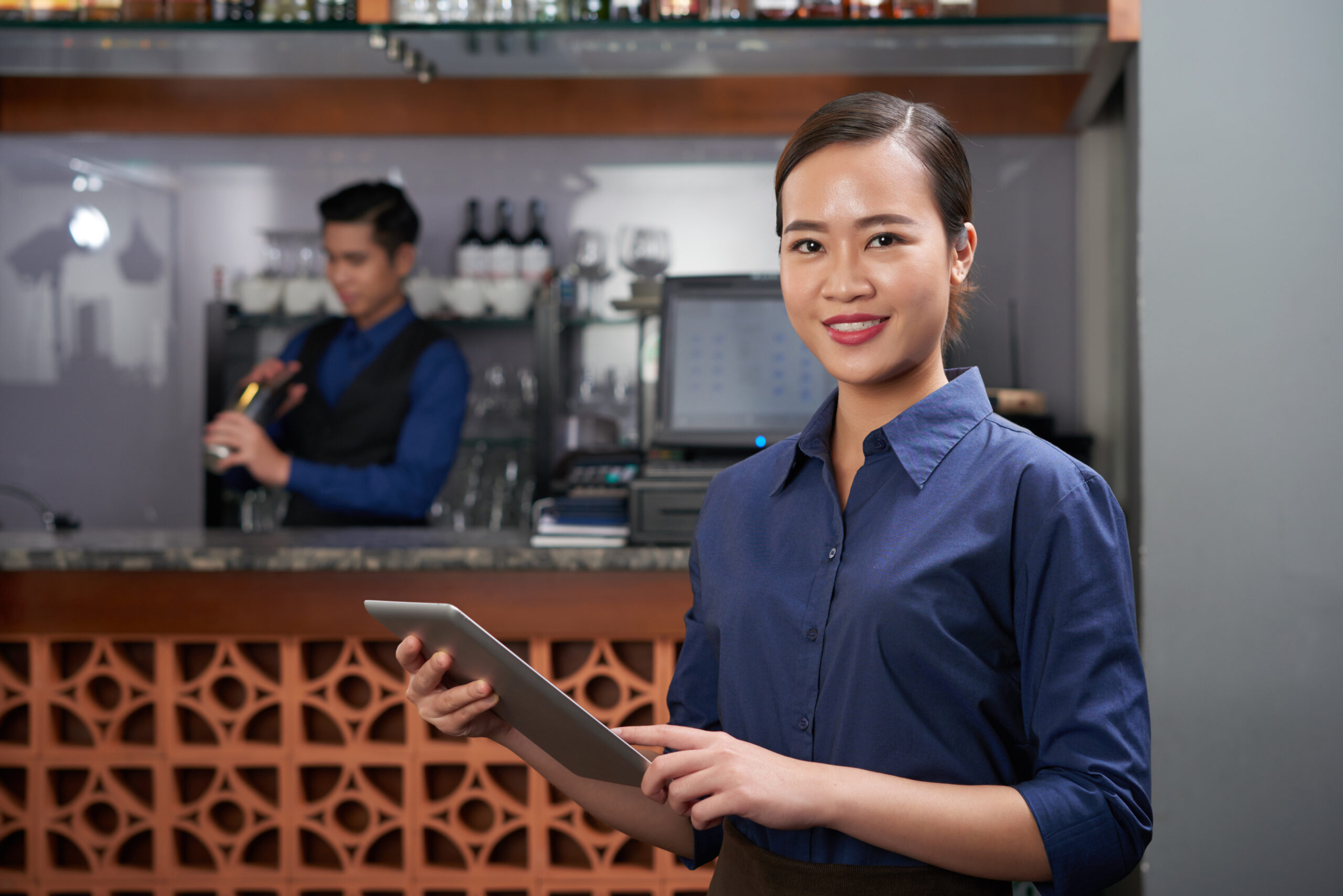 Pretty Vietnamese bar owner with tablet computer in her hands